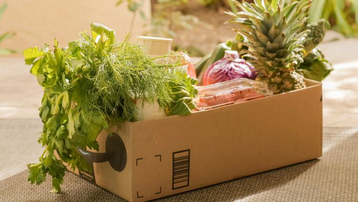 A cardboard box filled with fresh vegetables and fruits, perfect for delivery or online shopping.